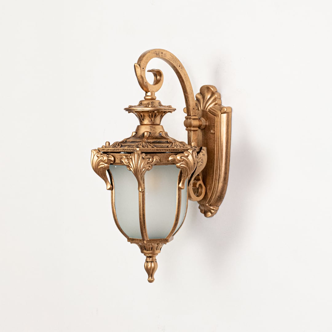 Classic gold metal wall lantern switched off on white background highlighting detailed metalwork and traditional lantern form.