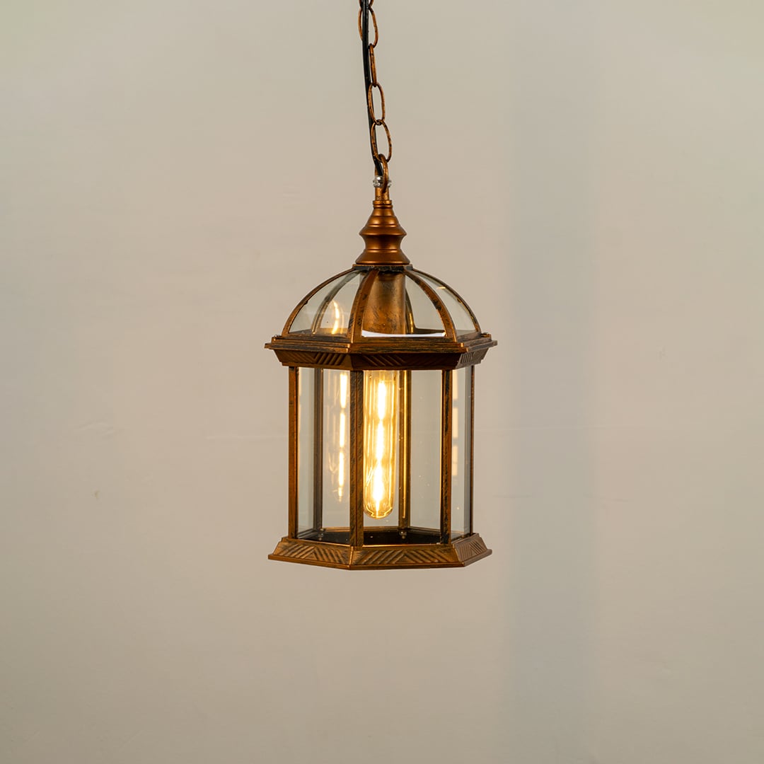 Bronze hanging outdoor lantern on white background with light on displaying warm illumination through clear glass panels and vintage dome top design.