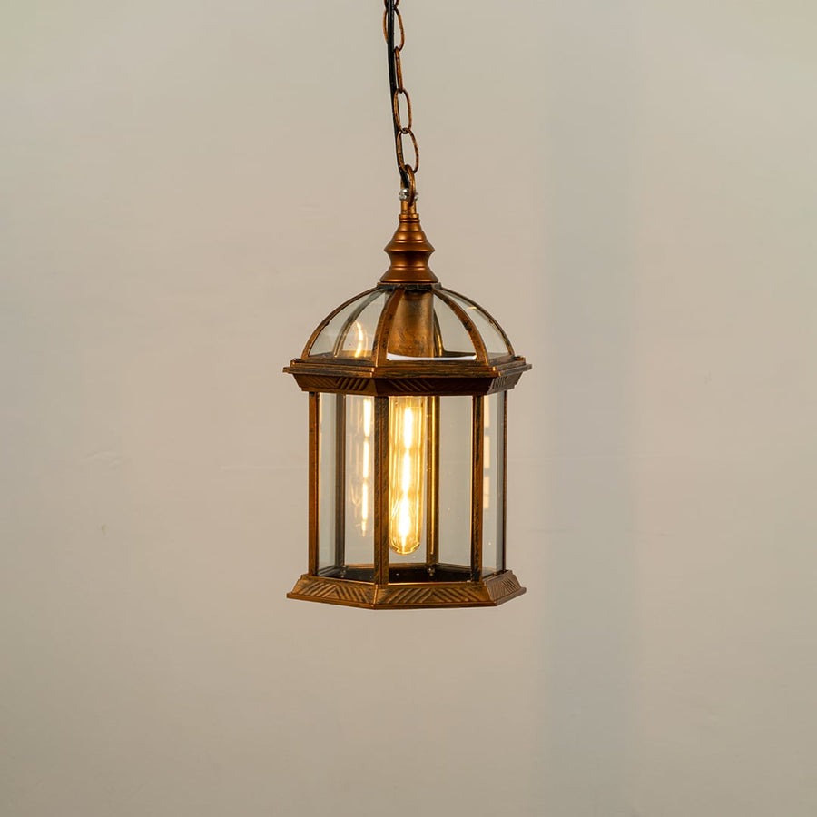 Bronze hanging outdoor lantern on white background with light on displaying warm illumination through clear glass panels and vintage dome top design.
