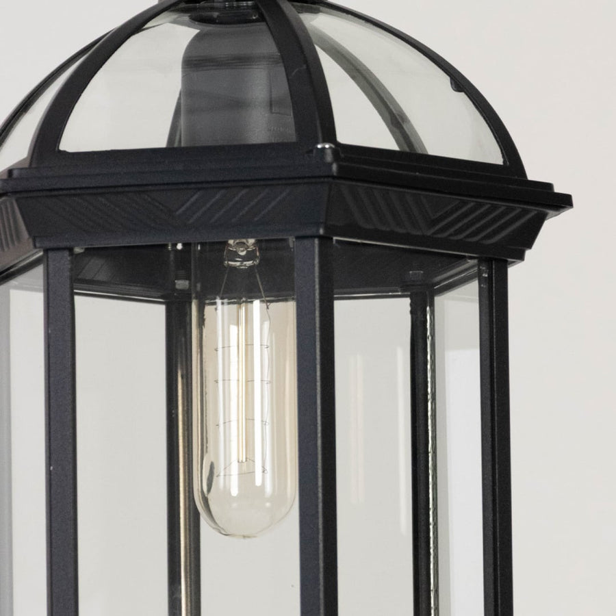 Black outdoor hanging lantern light glowing softly on white background showing detailed metal finish.