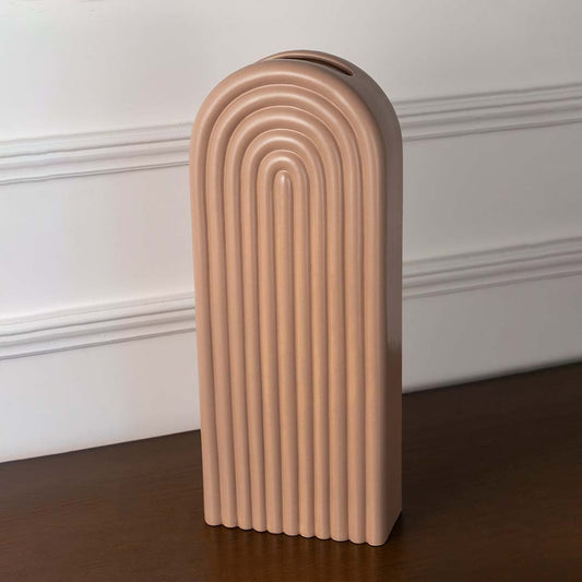 Tall matte taupe ceramic arch vase with a concentric ribbed rainbow pattern displayed on a wooden console table top.