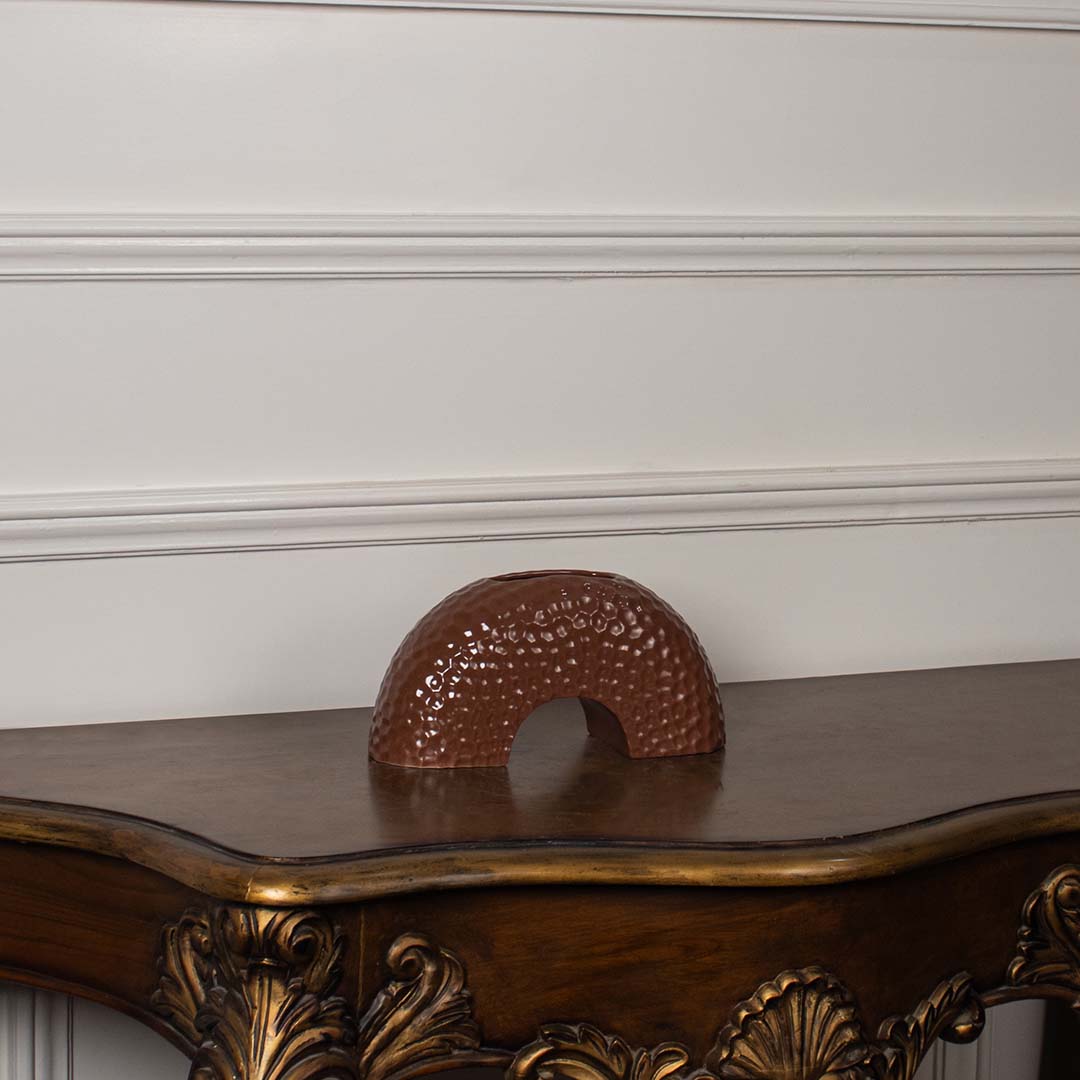 Brown arched ceramic vase displayed on a clean white background  showing its textured surface and curved modern silhouette clearly.