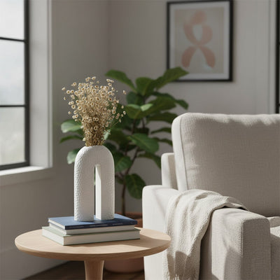 White ceramic U-shaped vase adding artistic modern touch to home decor with minimalist aesthetic appeal.