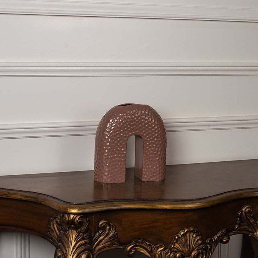 Brown arched ceramic vase displayed on a clean white background showing its smooth shape and textured finish.