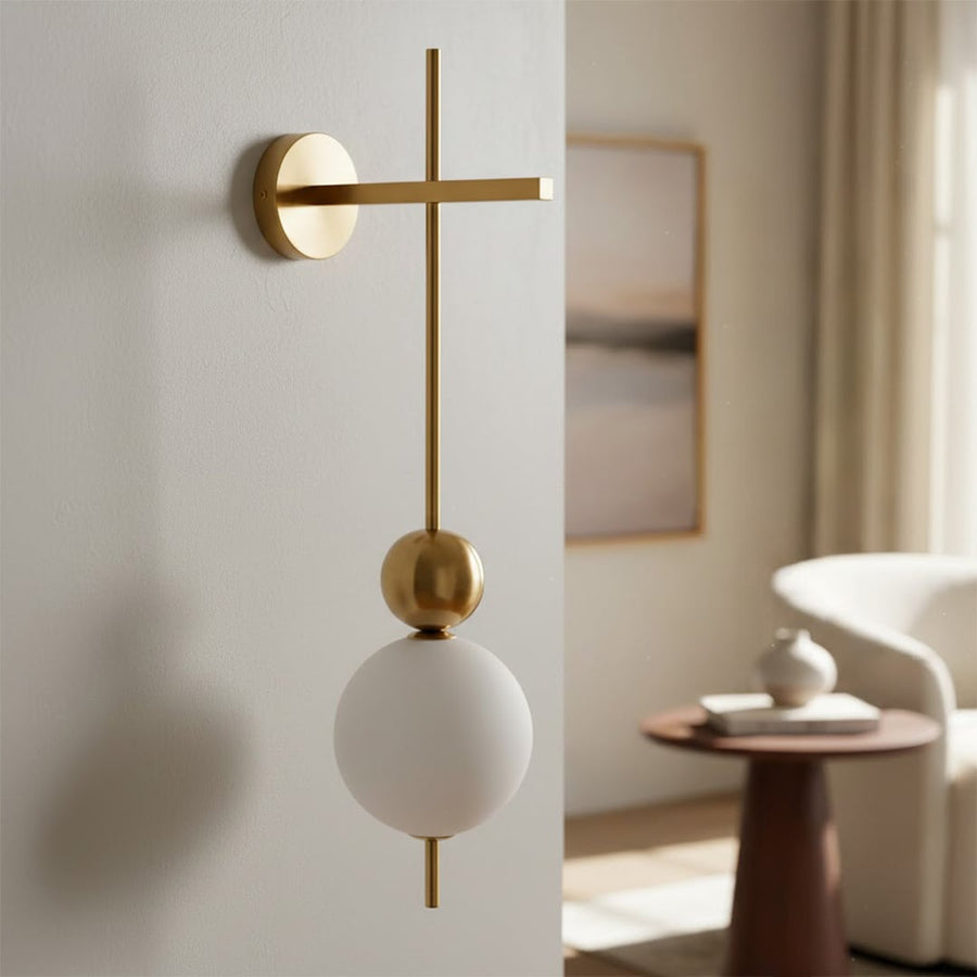 Modern gold metal wall light with white glass globe for elegant bedroom and luxury decor styling spaces.

