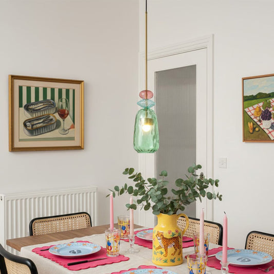 Turquoise and coral glass pendant light above dining table adding vibrant contemporary elegance.