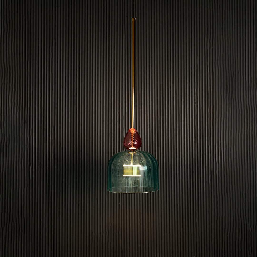Illuminated turquoise glass pendant light with coral accents creating warm ambiance for elegant spaces.
