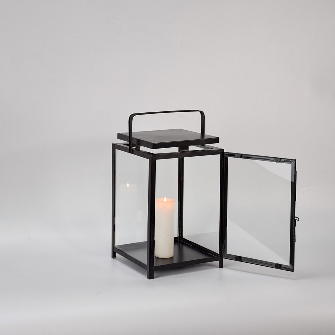 Black metal lantern with open glass door and candle holder for elegant indoor decor styling.