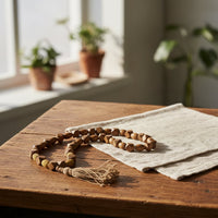 Brown bead garland placed on a rustic linen runner near sunlight enhancing the cozy natural decor aesthetic.