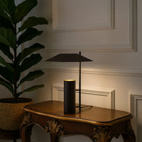 Dark brown metal table lamp with geometric shade adding modern elegance to tabletop decor in a stylish living room setting.