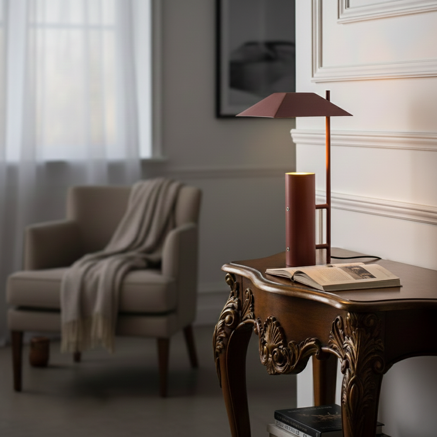 Contemporary red metal table lamp with geometric shade styled on wooden side table in an elegant living room.
