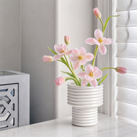 Artificial pink orchid flowers in a white ceramic vase adding elegant decorative charm to modern home interiors.