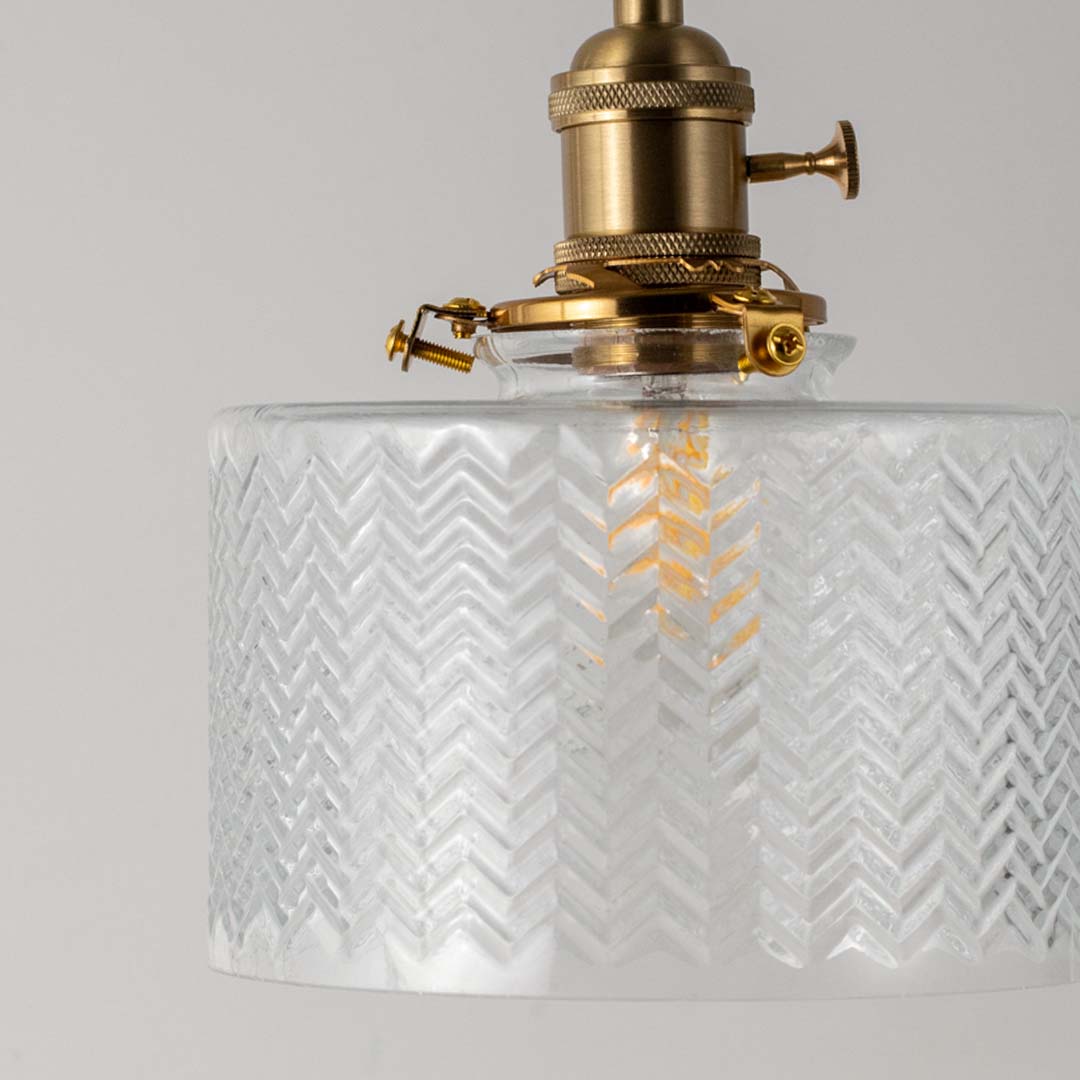 Closeup of textured clear glass and brass metal pendant light showcasing premium craftsmanship.