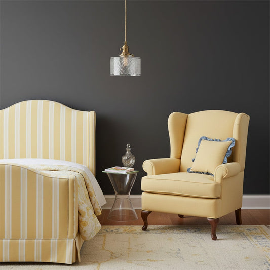 Textured clear glass and brass metal pendant light creating cozy ambience beside the armchair indoors.