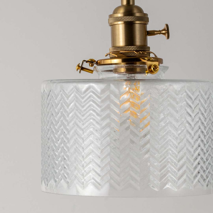 Closeup of textured clear glass and brass metal pendant light showcasing premium craftsmanship.