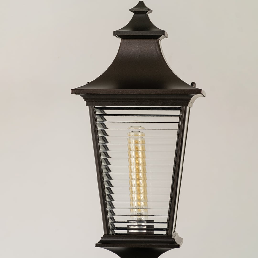 Black outdoor lantern Closeup Light On showing the ribbed glass texture and the bright vertical filament bulb.
