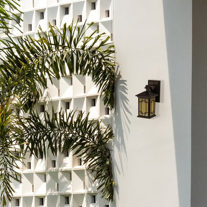 Elegant brown metal outdoor lantern with warm light on mounted on a bright exterior wall adding a soft welcoming glow to garden and patio spaces.