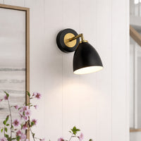 Elegant black and gold metal wall light mounted beside artwork for cozy bedroom and hallway decor styling.
