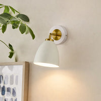Modern white and gold metal wall light mounted beside artwork for cozy bedroom and hallway decor styling.