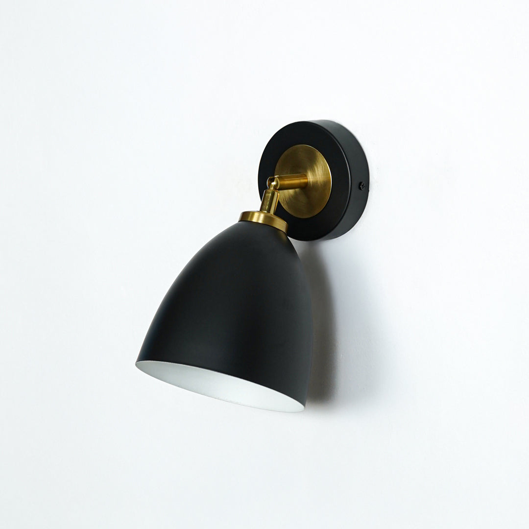 Elegant black and gold metal wall light with cone shade for stylish modern bedroom and hallway decor styling.