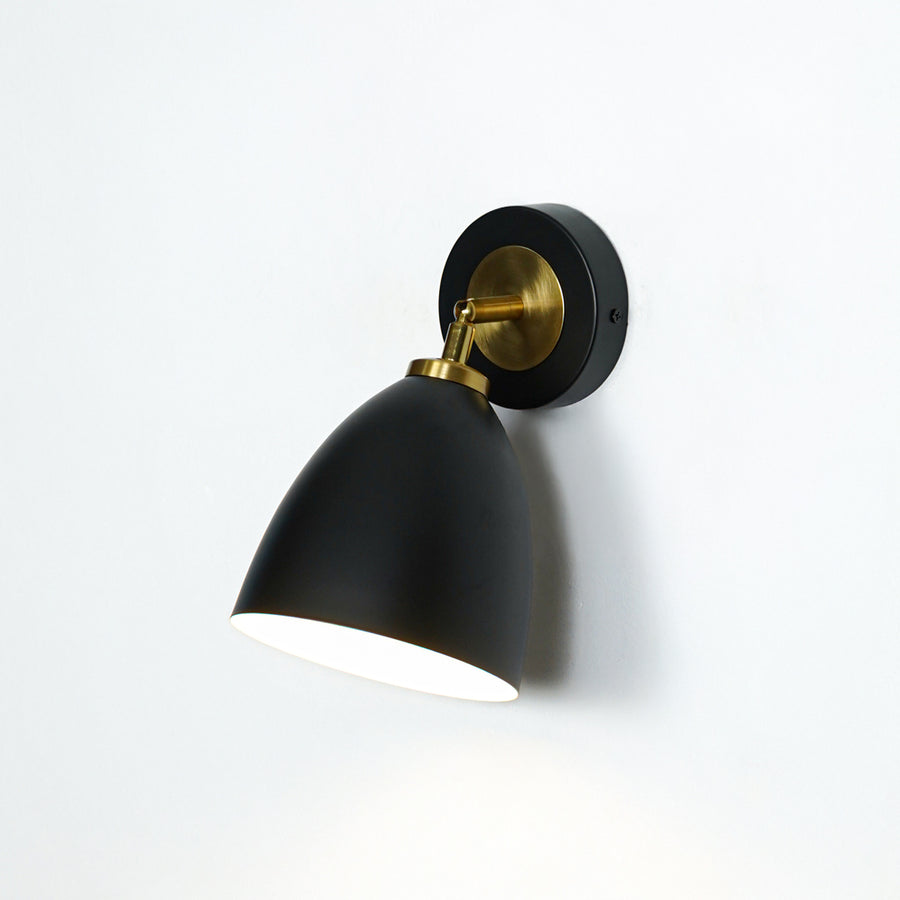 Modern black and gold metal wall light mounted on white wall for elegant bedroom hallway and living room decor.