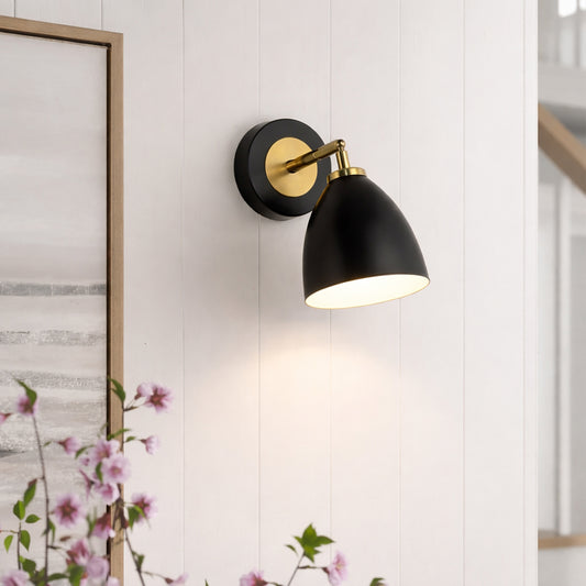 Elegant black and gold metal wall light mounted beside artwork for cozy bedroom and hallway decor styling.