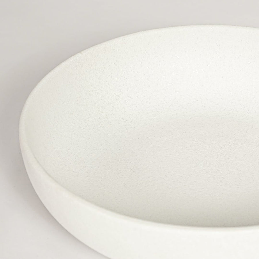 Closeup of matte white ceramic bowl with minimalist round shape ideal for elegant home decor shelf styling.
