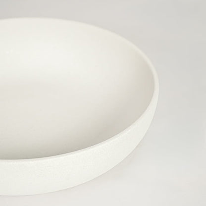 Detailed view of white ceramic serving bowl with smooth curved edges perfect for contemporary dining table decor display.