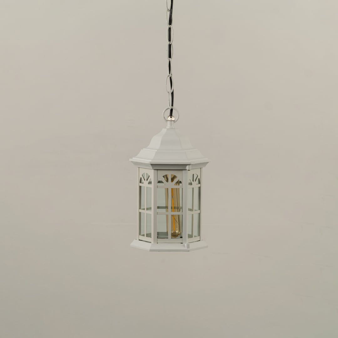White metal hanging lantern on white background with light off displaying clear glass windows and traditional hexagonal shape suitable for outdoor ceilings.