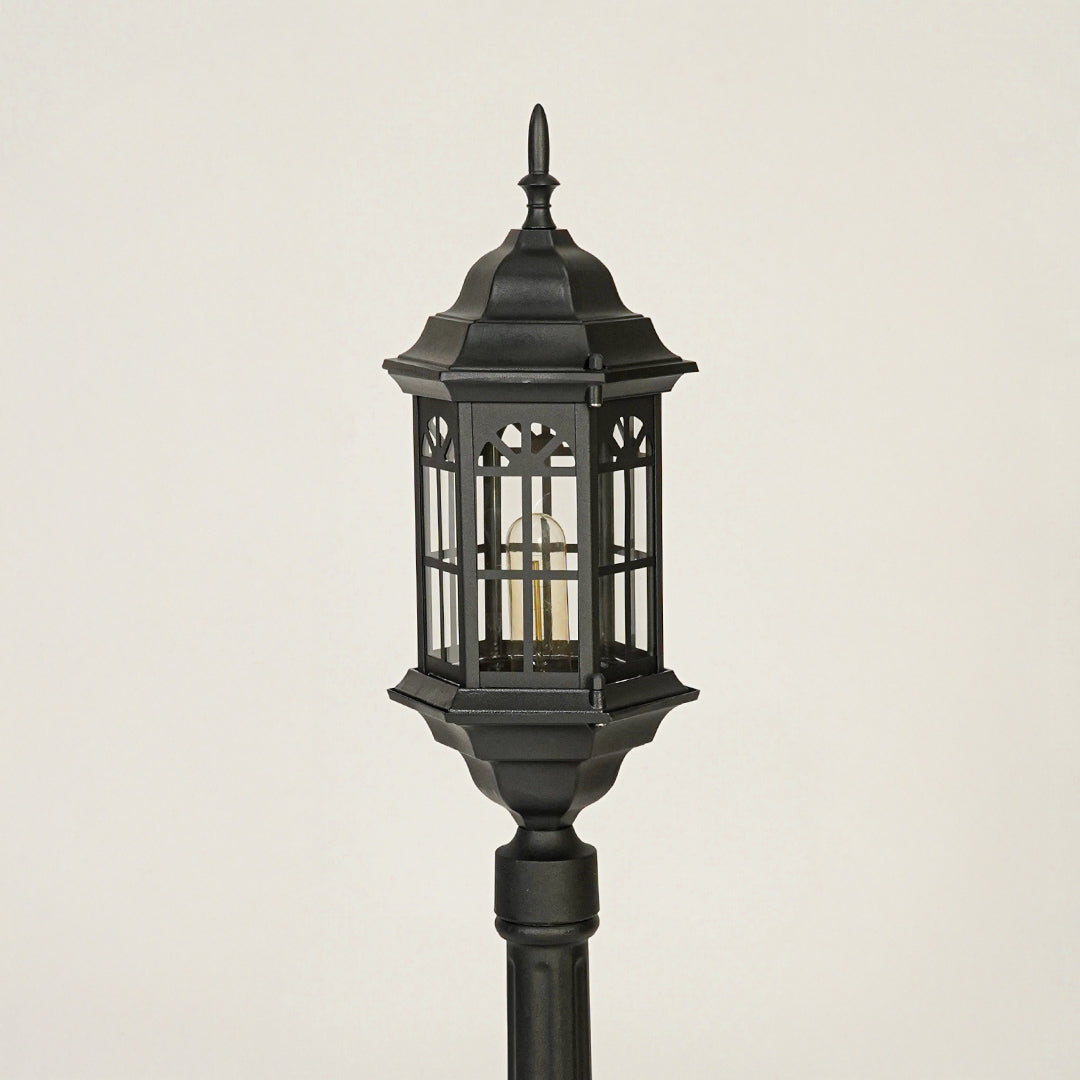 Close view of black outdoor lantern pole light with glass enclosure showcasing durable weather resistant exterior lighting design.