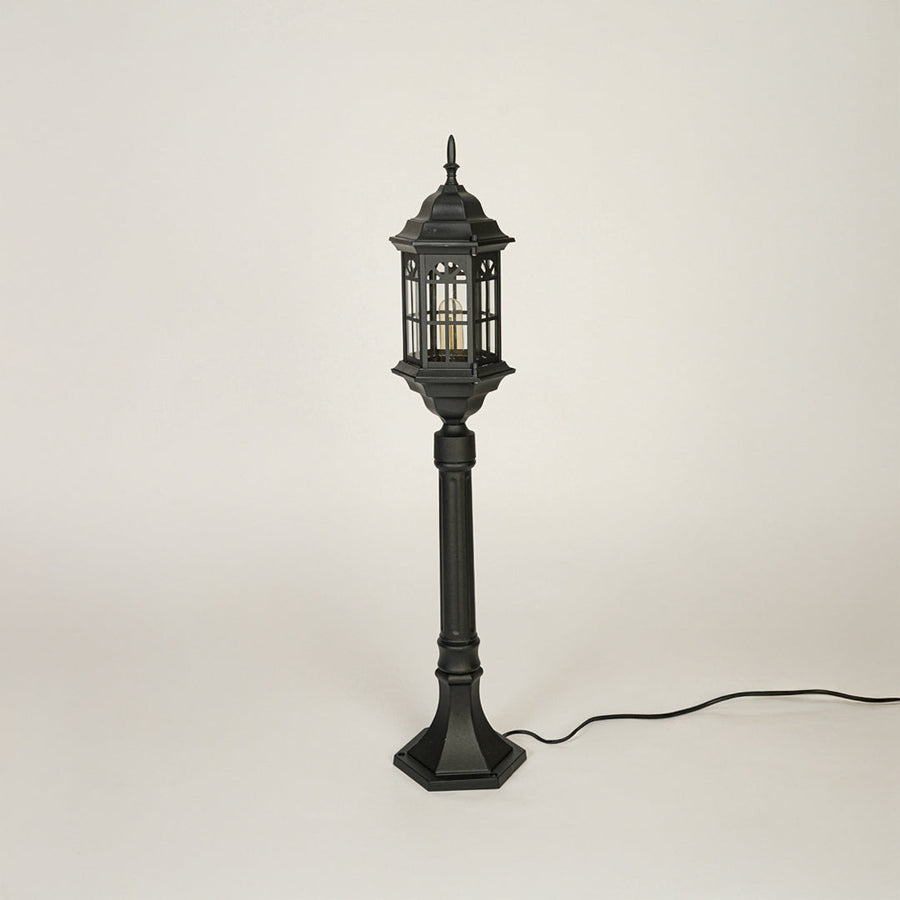 Traditional outdoor pole light with decorative lantern top and black metal body on clean background ideal for garden or patio lighting.