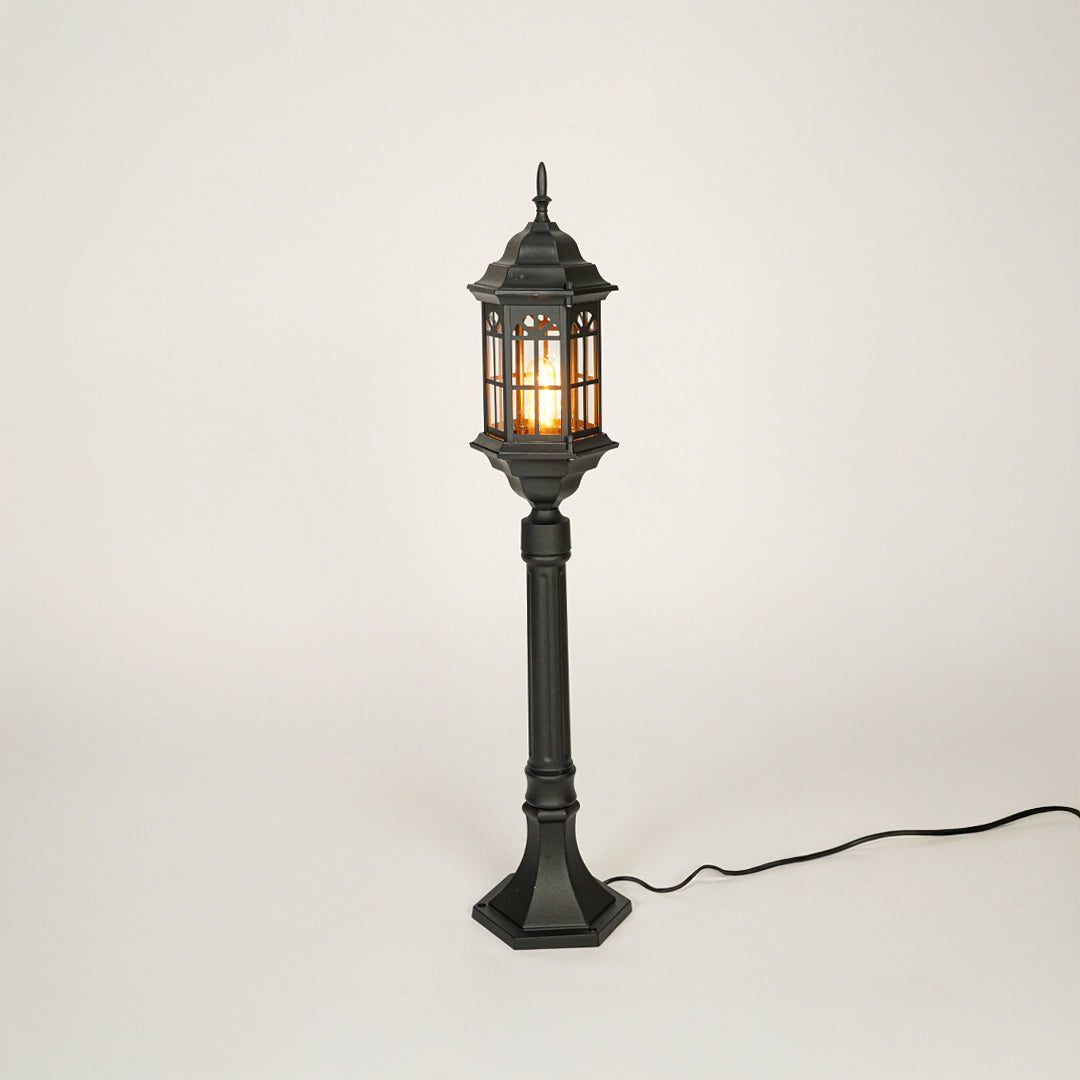 Vintage style black metal garden lamp post with clear glass panels on neutral background perfect for outdoor lawn or driveway lighting.