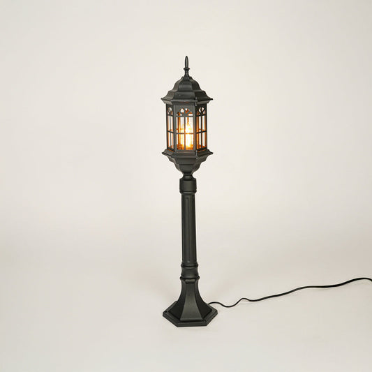 Vintage style black metal garden lamp post with clear glass panels on neutral background perfect for outdoor lawn or driveway lighting.