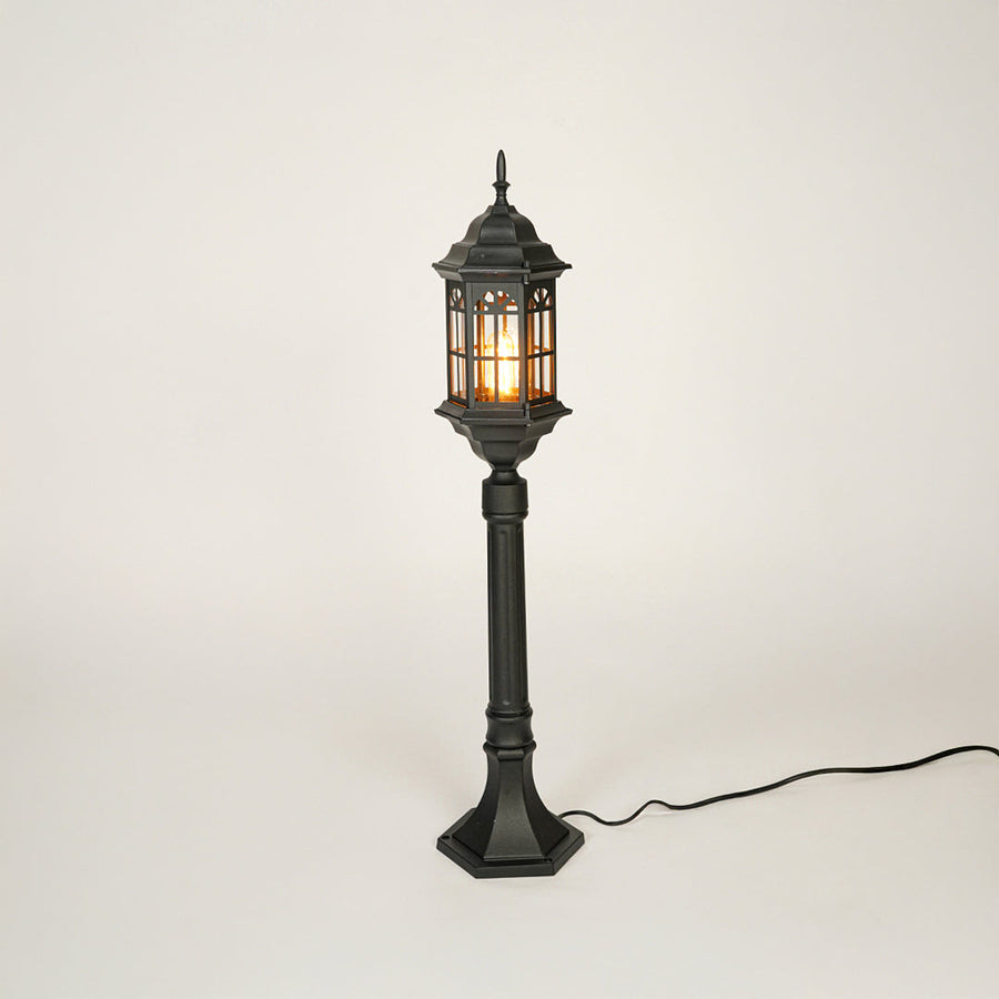 Vintage style black metal garden lamp post with clear glass panels on neutral background perfect for outdoor lawn or driveway lighting.