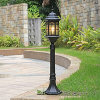 Black outdoor garden pole light with classic lantern design installed along curved pathway in landscaped garden ideal for pathway lighting.