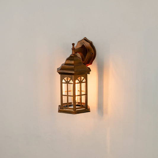 Antique brass outdoor wall lantern on white background with an arched paneled glass shade for vintage porch decor.