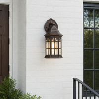 Vintage bronze metal arched cage glass wall sconce lantern on white brick exterior facade for rustic home entryway porch.