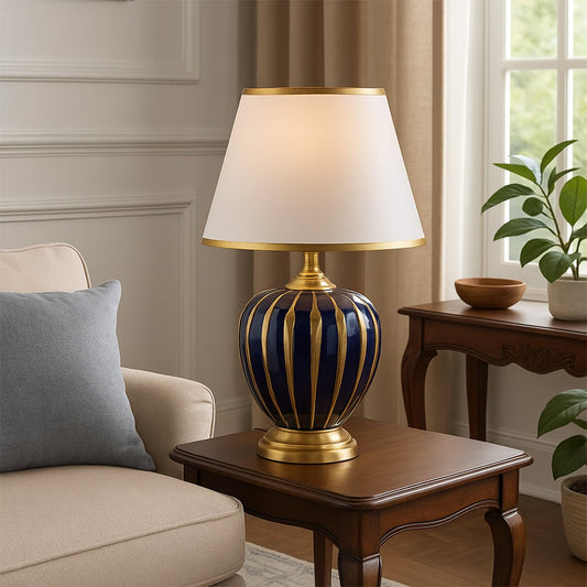 Blue ceramic table lamp with golden striped design and fabric shade adding luxury lighting to living room decor.