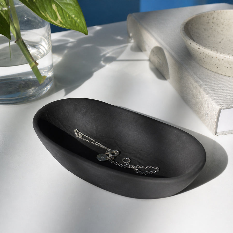 Black textured ceramic decorative tray placed on table for elegant contemporary home decor styling.