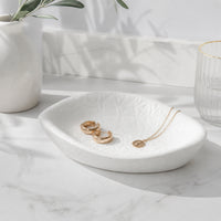 White ceramic decorative tray with jewelry placed on marble table for elegant modern decor styling.