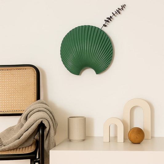 A modern decorative wall plate in a deep green tone showcasing a textured shell inspired design that adds a stylish artistic touch to contemporary home decor.