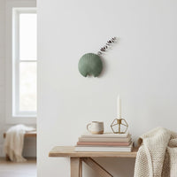 Green shell shaped wall decor shown in a clean minimal setting adding a modern accent to indoor home styling.