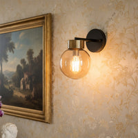 Wall light with amber glass globe and black metal mount placed on textured wall adding warm ambient lighting to elegant living room decor.