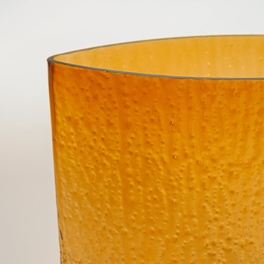 Close up view amber textured glass planter showing hammered surface glossy finish decorative glass accent for modern home styling.