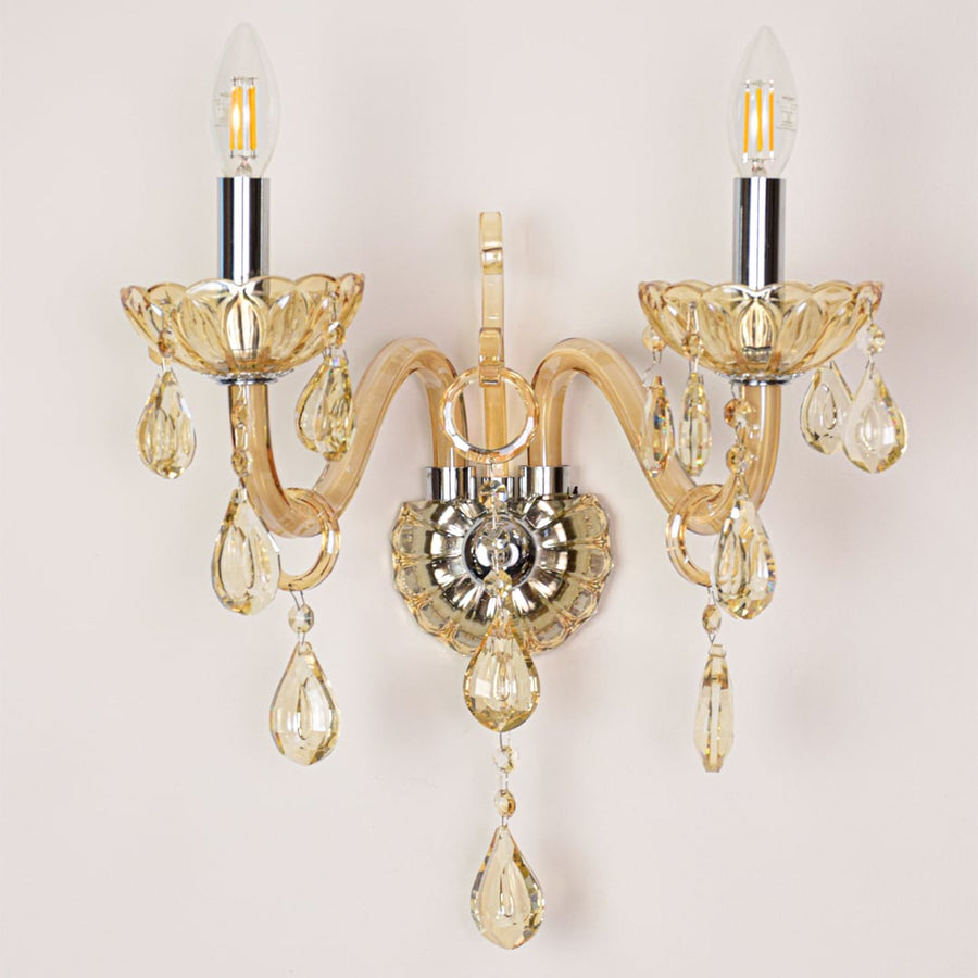 Closeup of golden crystal wall light with hanging crystal droplets and curved arm perfect for luxury wall decor.