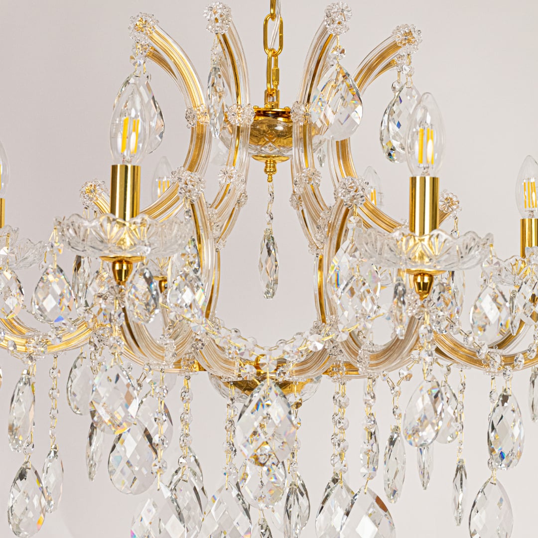 Closeup of gold crystal chandelier arms and hanging drops showing fine detailing for premium home lighting.