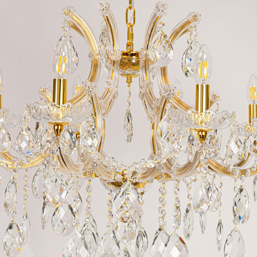 Closeup of gold crystal chandelier arms and hanging drops showing fine detailing for premium home lighting.