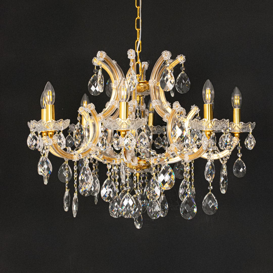 Gold crystal chandelier with clear crystal drops displayed on black background for a bold luxurious decor effect.
