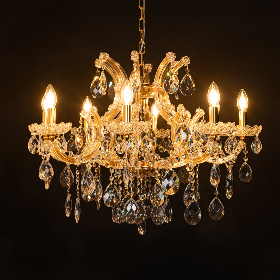 Gold crystal chandelier glowing against black background highlighting sparkling crystals and luxury lighting style.