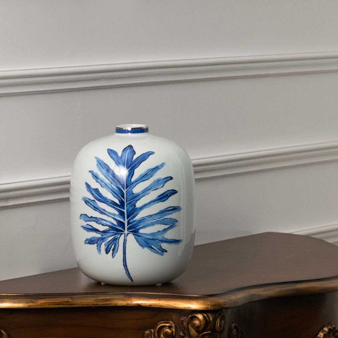 White ceramic jar with blue leaf artwork in a front view ideal for modern décor styling and elegant tabletop placement.